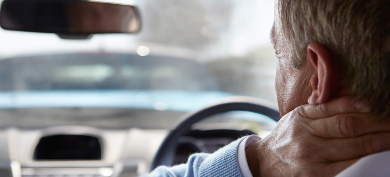 A man holds the back of his neck due to whiplash.